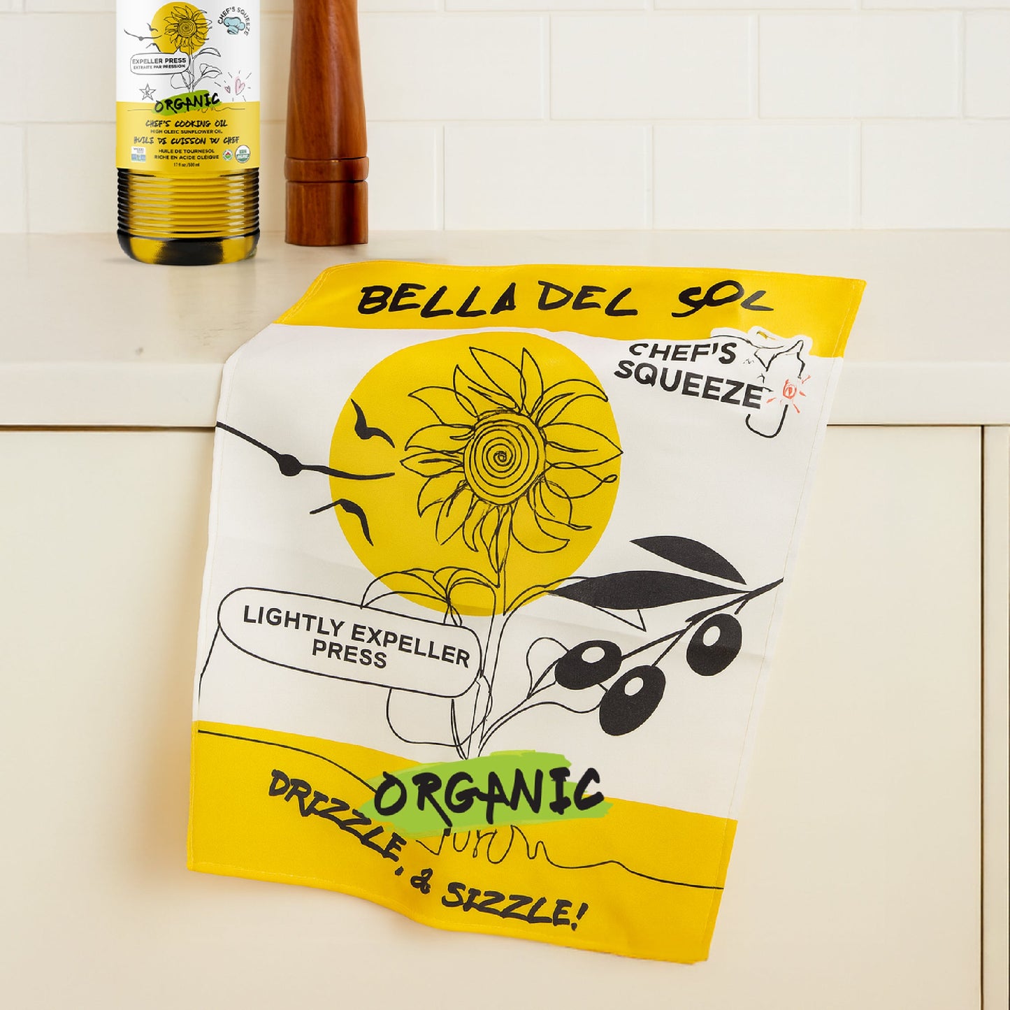Bella Del Sol tea towel with branded logo, laid out on a kitchen counter, showcasing its soft cotton texture and everyday utility.