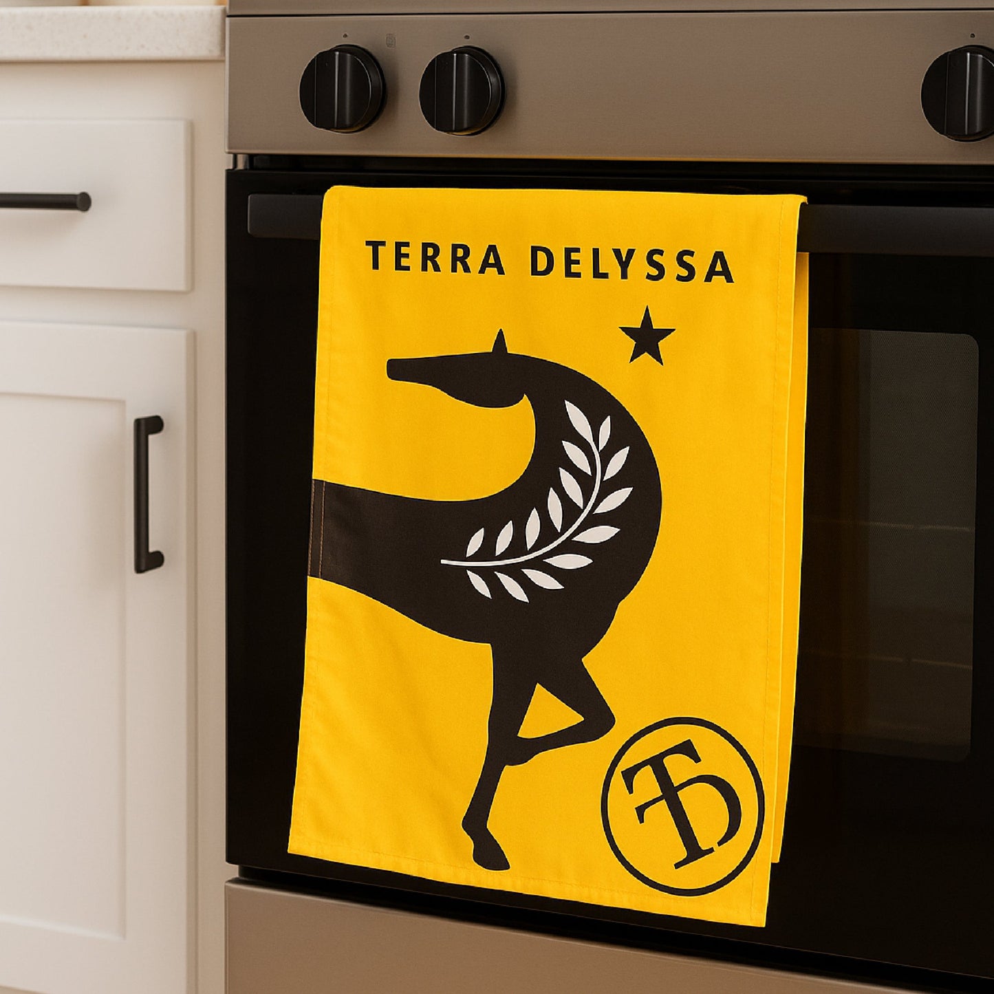 Terra Delyssa tea towel with traditional yellow and black horse branding hanging neatly on an oven handle in a kitchen setting.