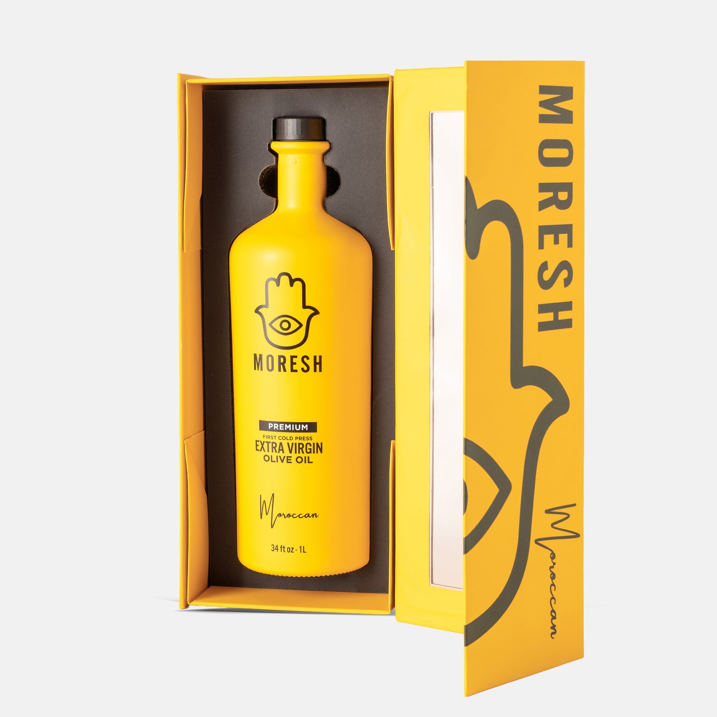A bottle of MORESH Premium Extra Virgin Olive Oil in a bright yellow glass bottle with a black cap, presented inside an open yellow gift box with the brand name 'MORESH' printed on the side.
